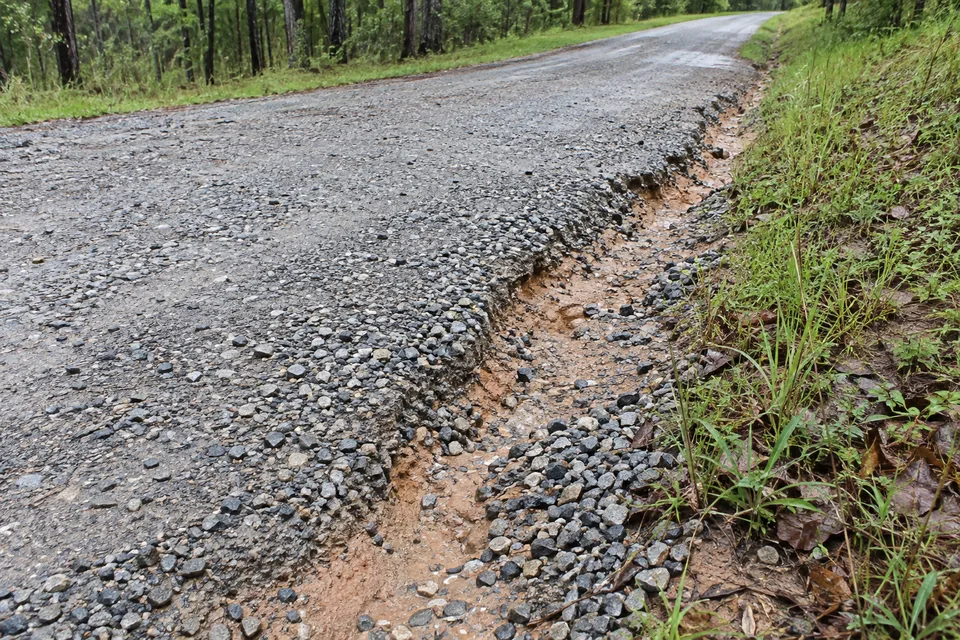 Eroded gravel driveway edge after runoff washed material away