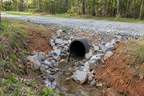 New culvert installation carrying runoff beneath a driveway