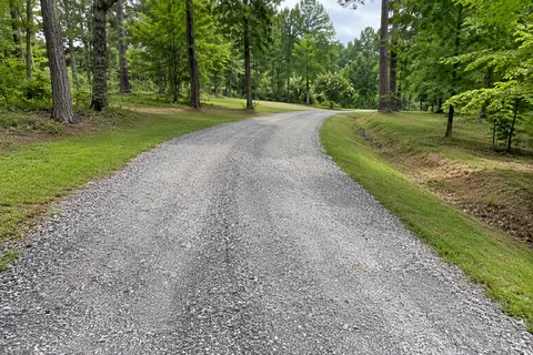 Compact track loader restoring the crown of a gravel driveway