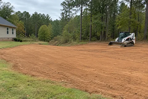 Track loader grading and smoothing a residential yard